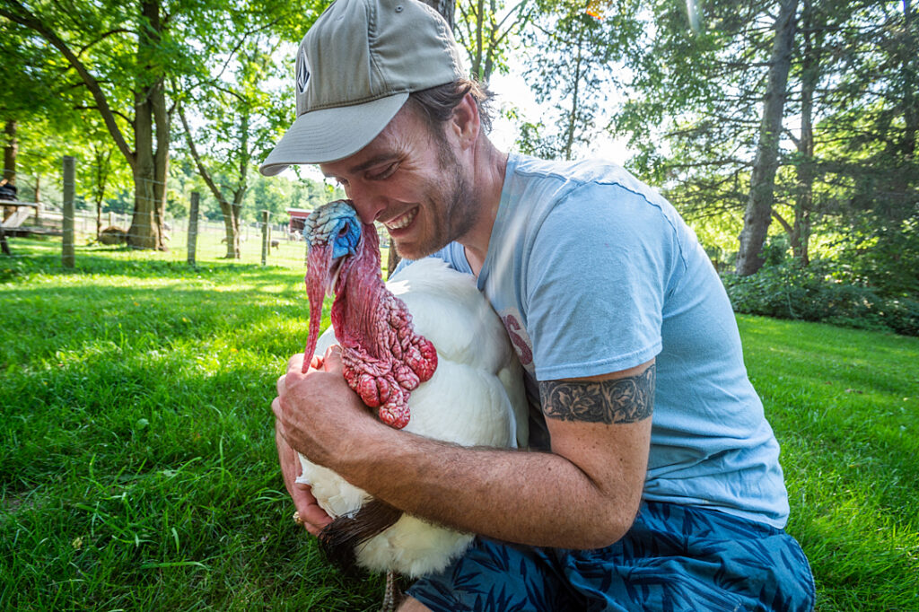 A person hugging a turkey to his chest.