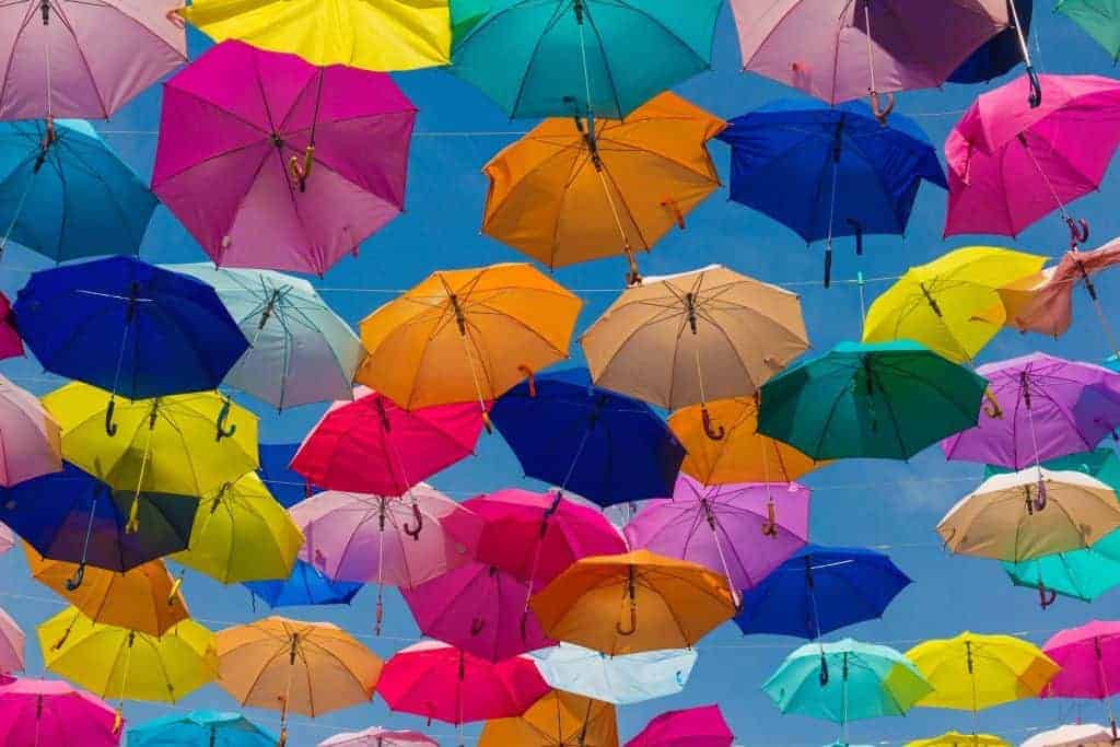 Many colorful umbrellas suspended from lines in the sky.