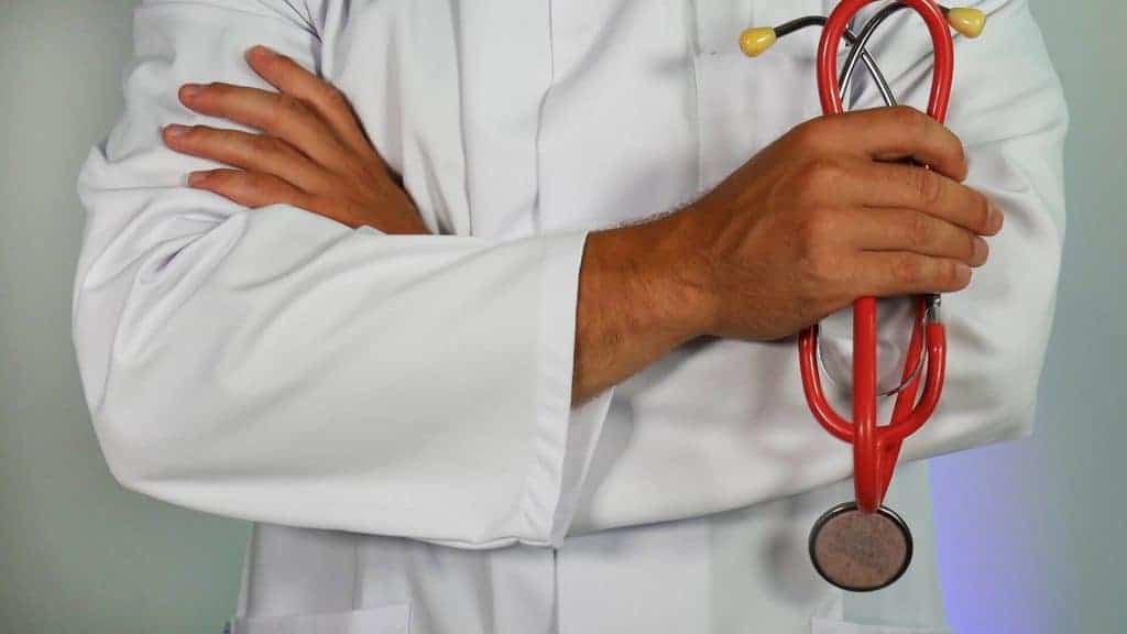 A veterinarian in a white coat holds a stethoscope.