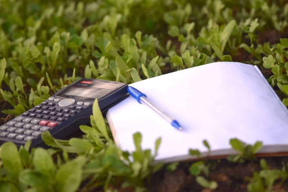 A calculator and pad and paper outside on grass.