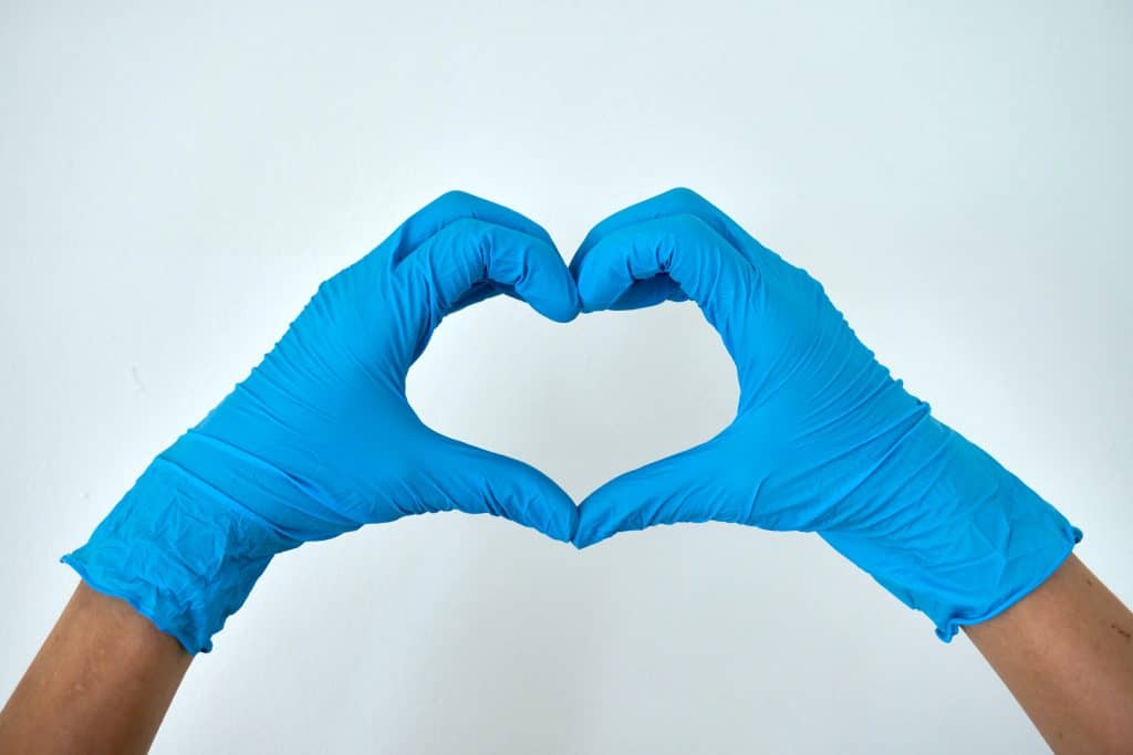 hands in blue medical gloves creating a heart shape