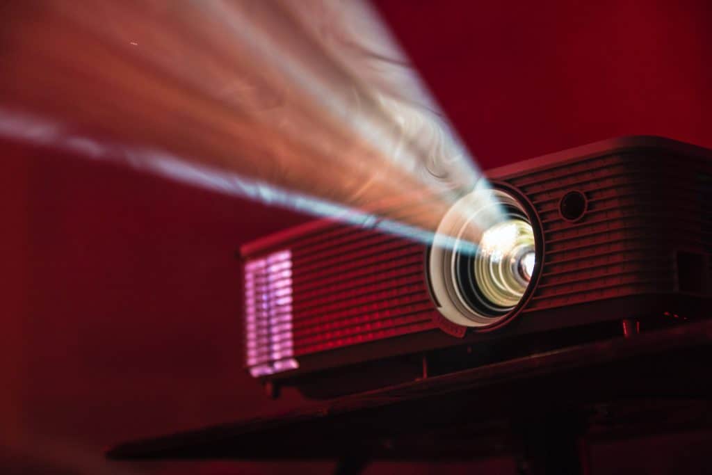 Close-up of a film projector. The background is dark red.
