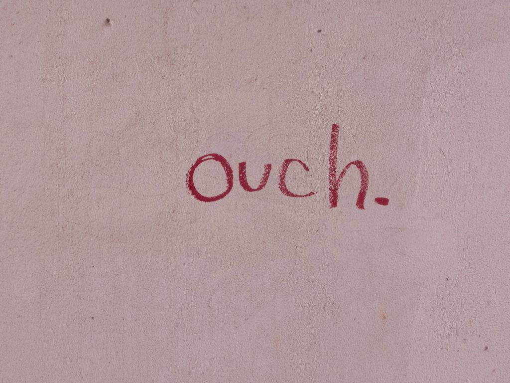 Pink note paper with the word "ouch' written in red.