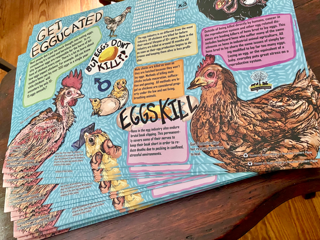 A close up photograph of a colorful hand-drawn educational poster which is titled "Get Eggucated". The background of the poster is blue and there are two large illustrated chickens on either side. The chicken on the left is mostly featherless and the chicken on the right has feathers. Both of them are debeaked. There are yellow chicks hatching from eggs in the middle and there is an illustration of a hen's reproductive tract in the top right corner. There are green, yellow, pink, and orange text boxes spread across the poster with informative text about the egg industry inside each. There is large black text in the middle of the poster that says "Eggs Kill".