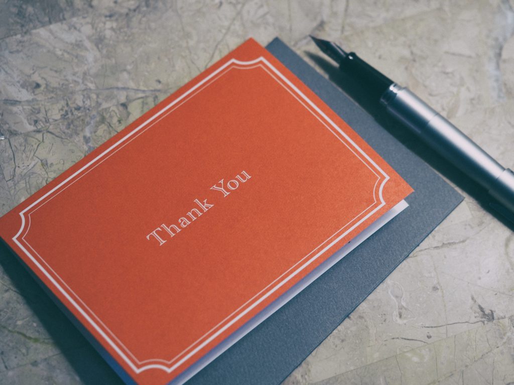 An image of a pen with a red pad reading "thank you."
