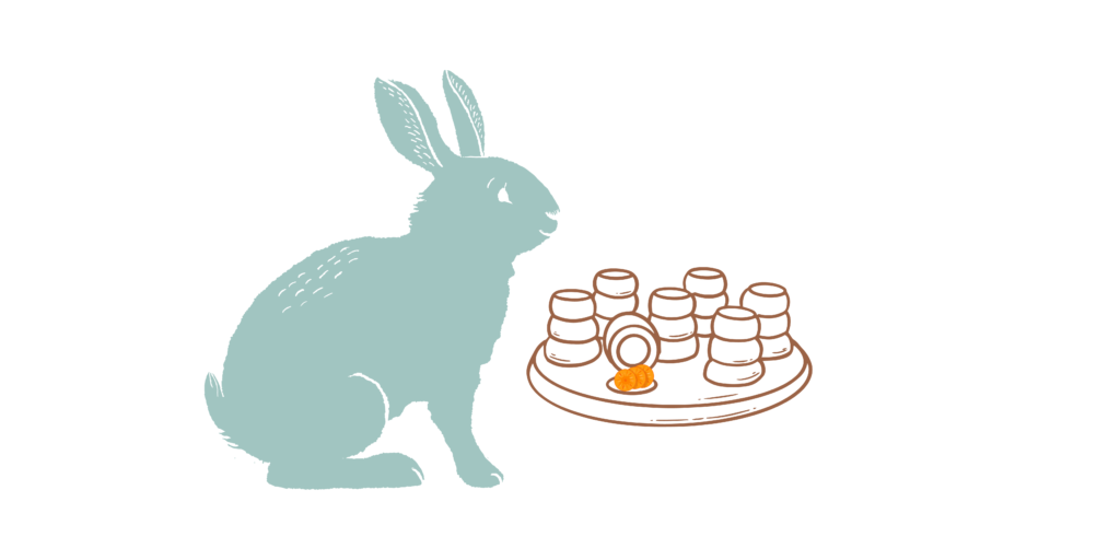 A blue cartoon rabbit sits in profile, looking at a wooden treat game where carrot slices are hidden under cups.