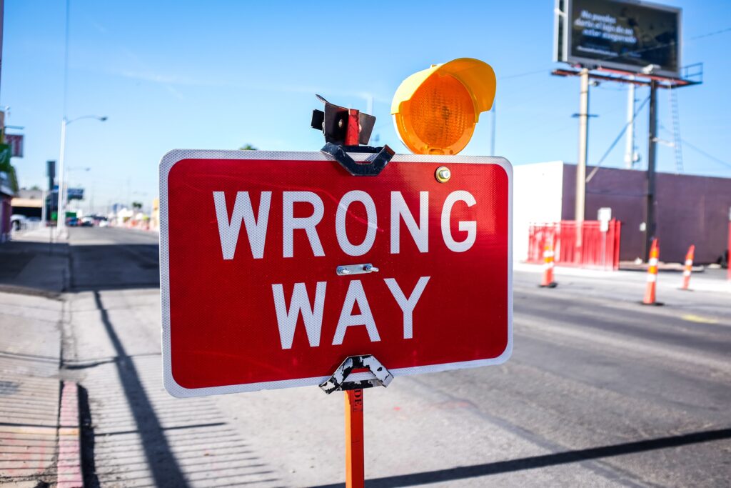 Photograph of a large red and white road sign that says "wrong way".