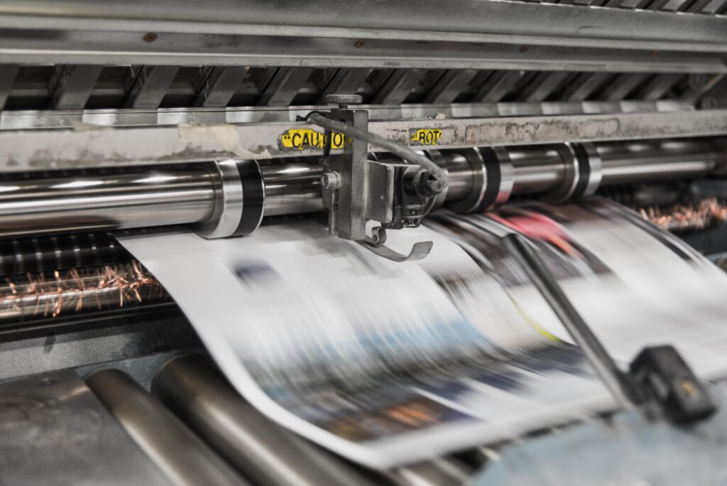 An image of a printing press, printing out newspapers.