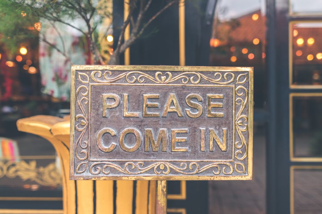 A close-up of a metal sign that says, "please come in".
