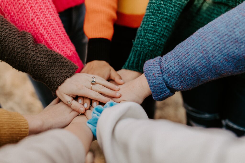 A photograph of a group of people's hands stacked on top of one another.