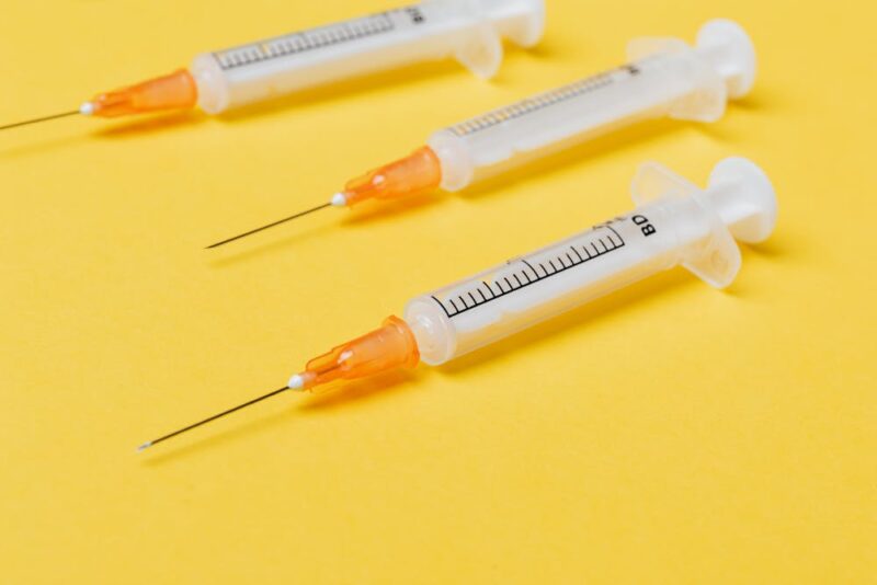 Three empty syringes on a yellow surface.