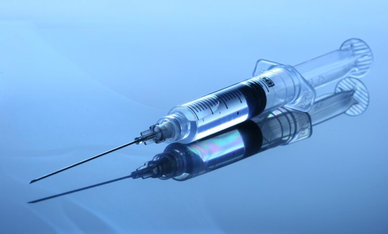 Needle and syringe against a blue background