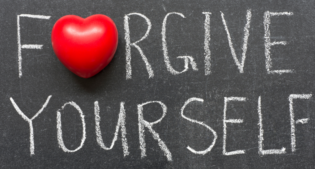 The words "Forgive Yourself" are scrawled across a chalkboard. The "o" in forgive is a red heart.