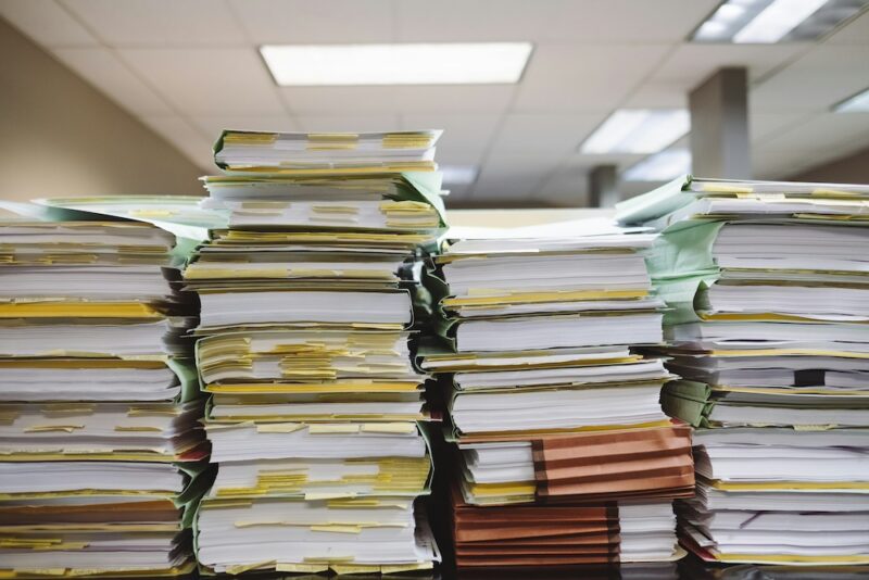 Four tall stacks of file folders full of papers.