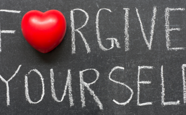 The words "Forgive Yourself" are scrawled across a chalkboard. The "o" in forgive is a red heart.