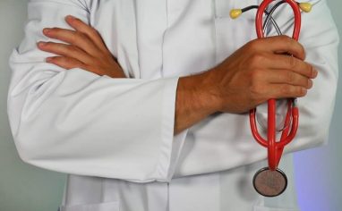 person with white coat holding stethoscope