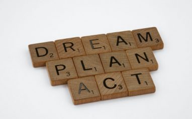 An image of three words stacked and spelled out by Scrabble blocks. The first reads: Dream. The second reads: Plan. The third reads: Act.